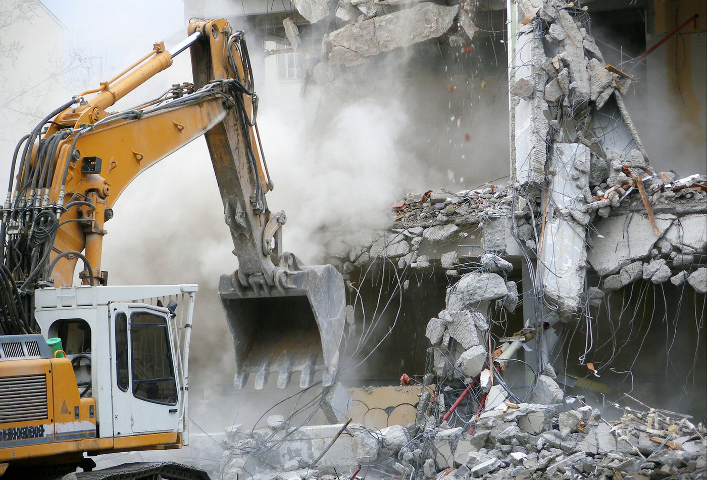 Excavator carrying out structural demolition of a building
